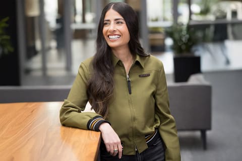 Official portrait of Asha Sharma, smiling in a dark jacket against a neutral background.